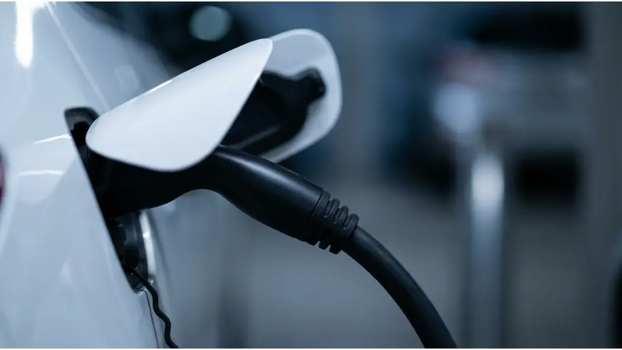Connecteur de recharge branché sur le véhicule, borne floutée en arrière-plan